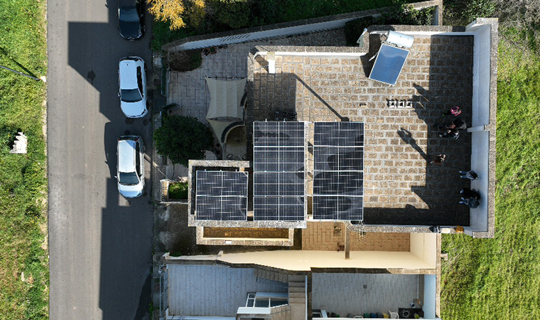 Vogelperspektive einer Dach-Solaranlage mit integriertem Solavita Hybrid-Wechselrichter und Batteriespeicher, die effiziente erneuerbare Energielösungen für Wohngebäude zeigt.