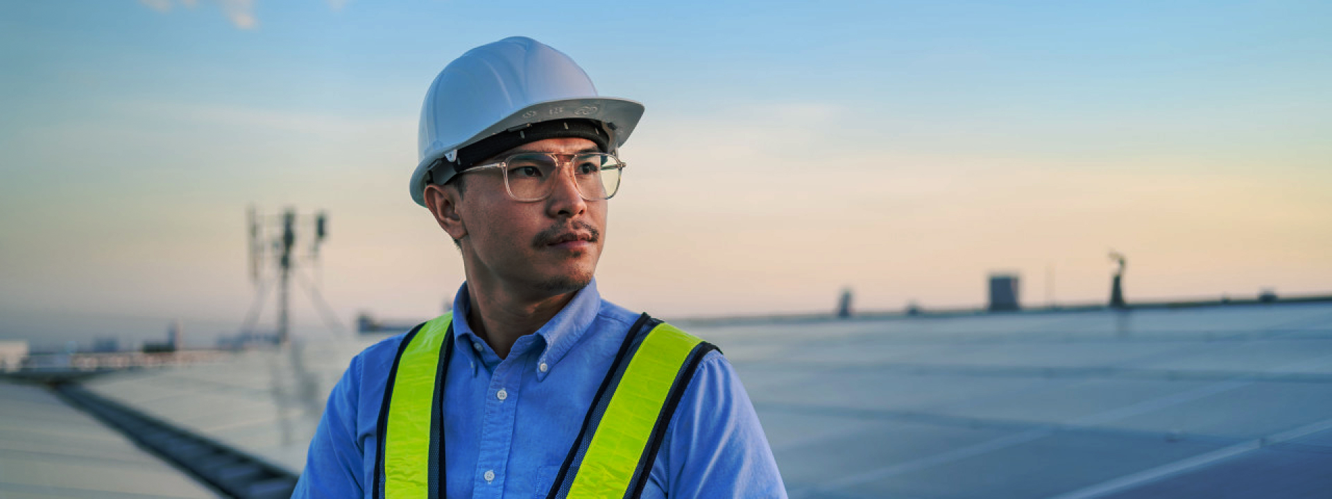 Techniker in Schutzausrüstung bei der Inspektion einer Solavita-Wechselrichter-Installation an einer Solarmodulreihe, mit Fokus auf die Sicherstellung der optimalen Systemleistung.